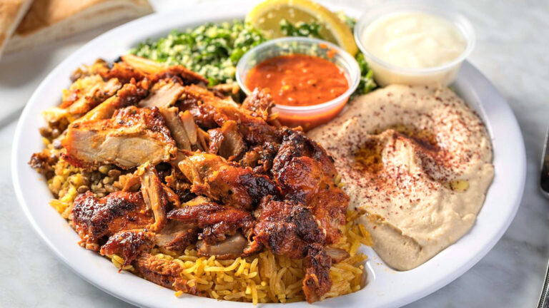 A close-up of a Chicken Shawarma Dinner from Sultan's Market: Which Consist in a Marinated spit roasted boneless chicken with a side of garlic sauce.