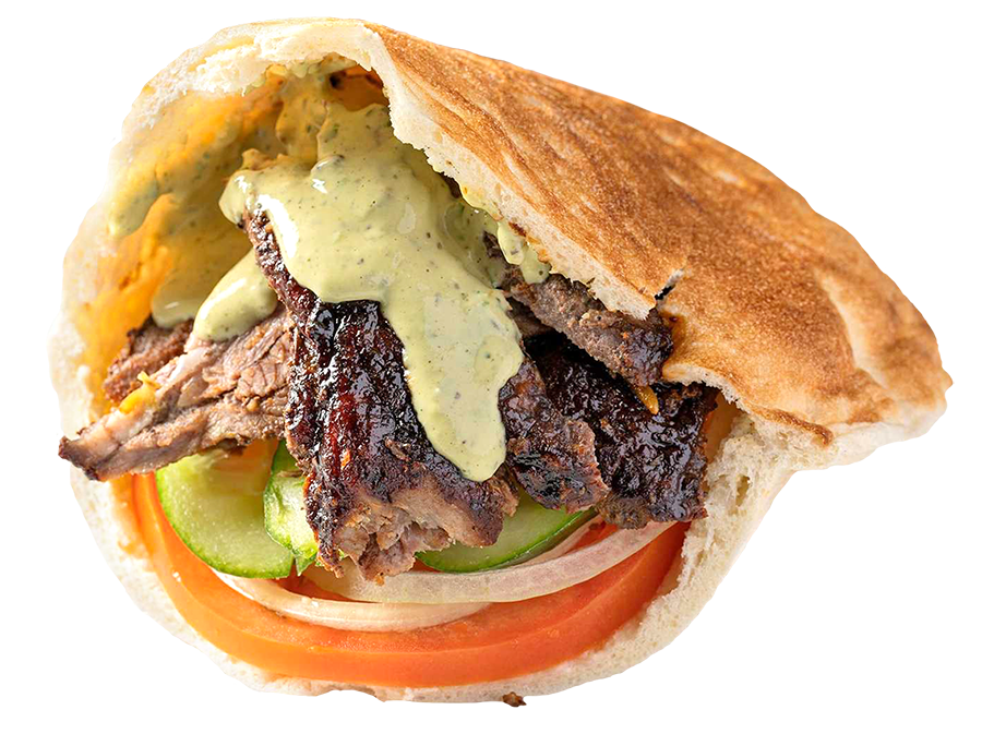 A Lamb Shawarma Sandwich: Marinated spit roasted lamb and beef thinly sliced lamb, served in a pita with hummus, onions, cucumbers, tomatoes and tahini sauce.