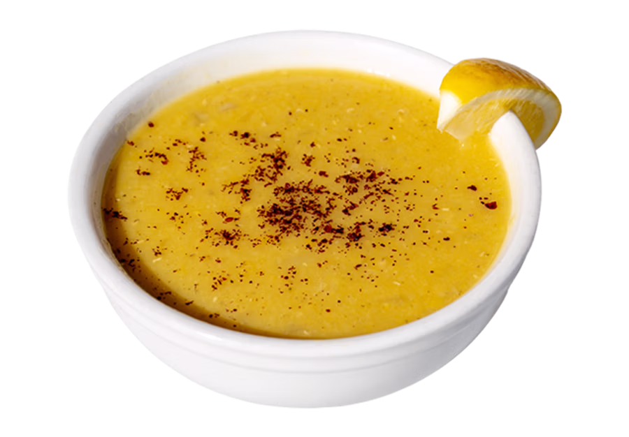 A bowl of Middle Eastern lentil soup garnished with herbs and lemon, prepared fresh at Sultan’s Market