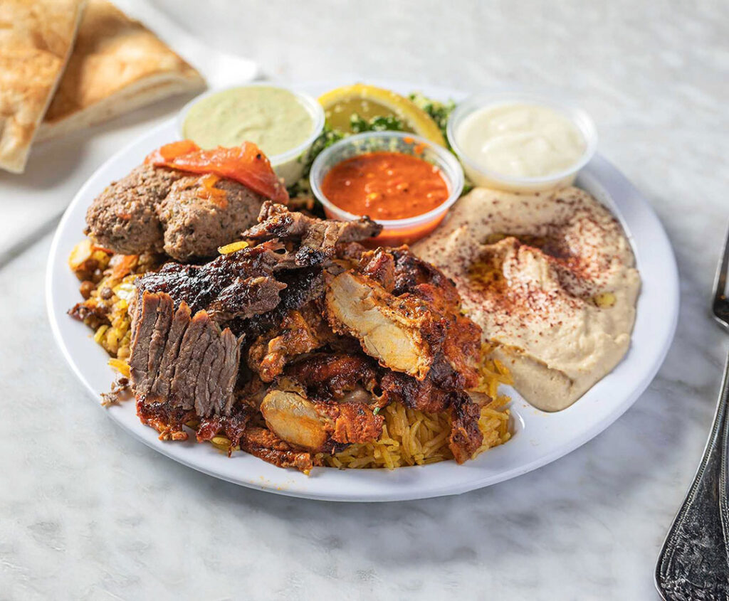 Sultan’s Market meat combo plate with sliced lamb and chicken shawarma, and kefta kabob, curry rice, hummus, pita bread, and house sauces